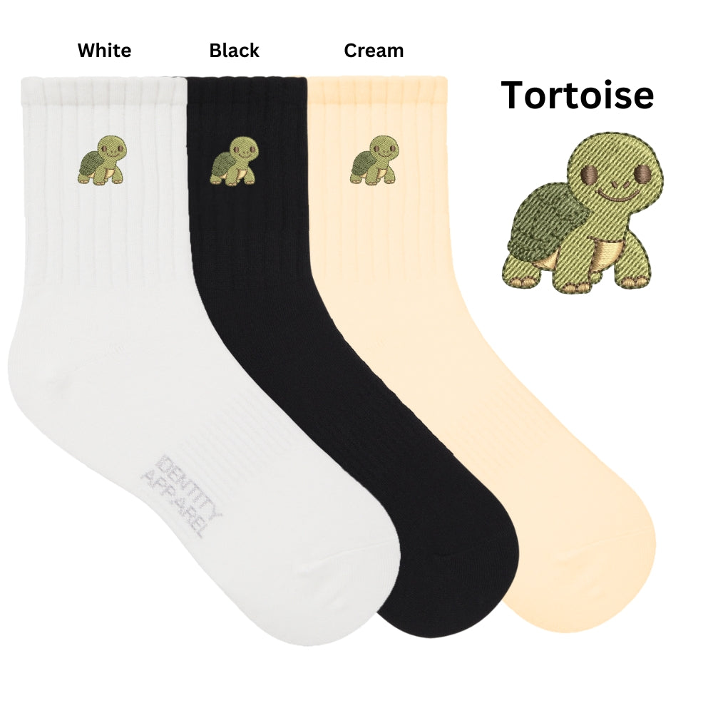 Three pairs of socks in white, black, and cream with tortoise design on a white background.