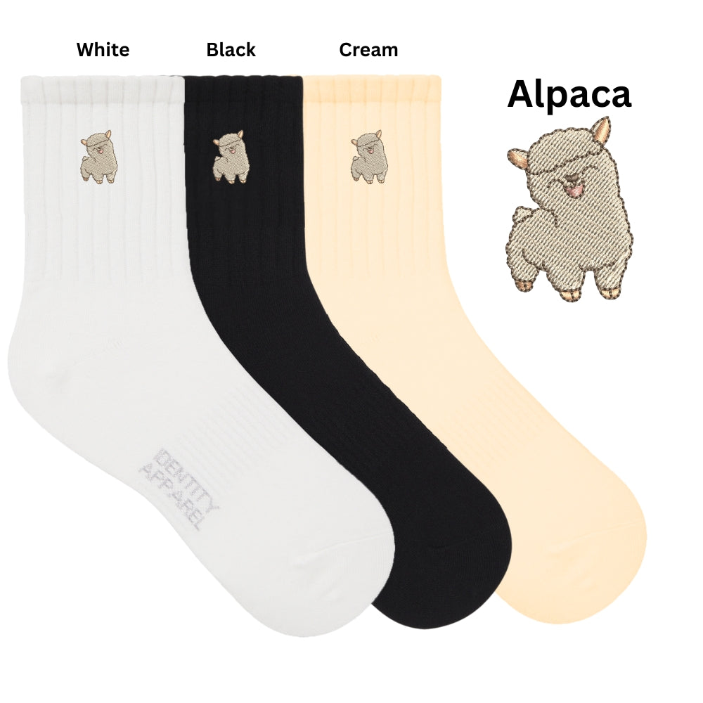 Three pairs of socks in white, black, and cream with alpaca designs on a white background.