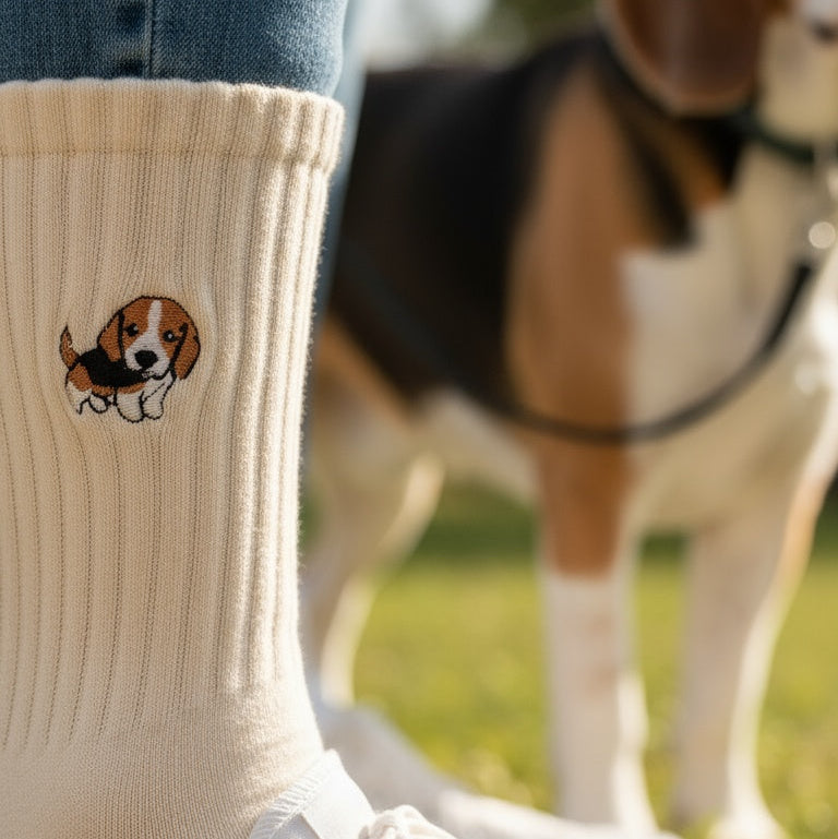 White sneakers with a dog design on socks, standing next to a dog in a grassy area.