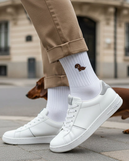 Person wearing white sneakers and beige pants with a dog in the background