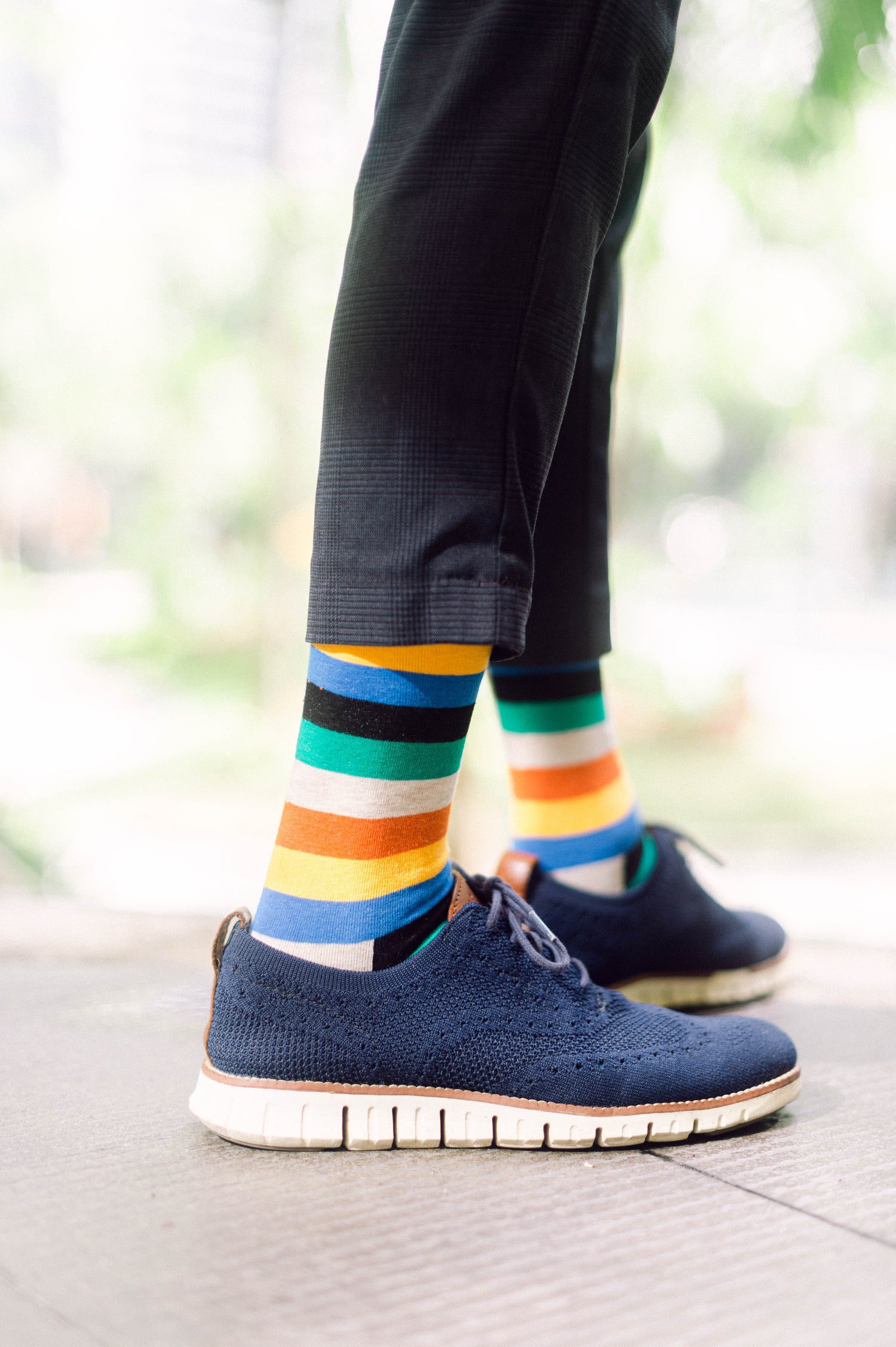 Man wearing blue sneakers and striped colorful printed socks