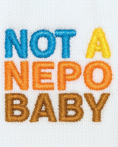 Embroidered text 'NOT A NEPO BABY' on a white background