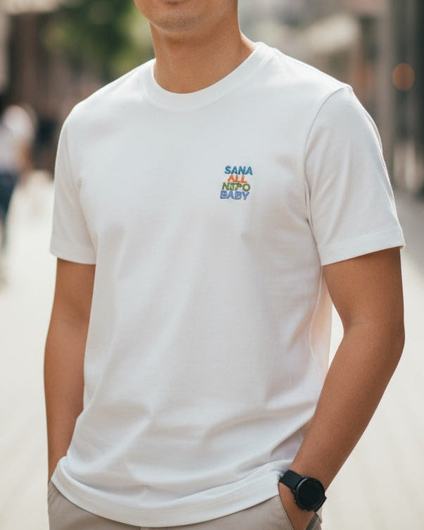 Person wearing a white t-shirt with colorful text on a blurred street background