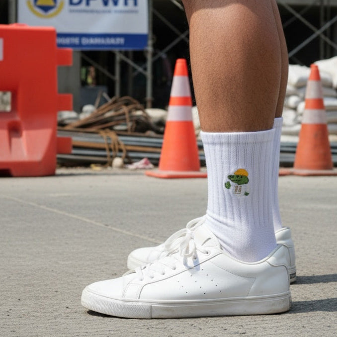 Person wearing white sneakers and socks with a logo, standing on a construction site with DPWH signage.